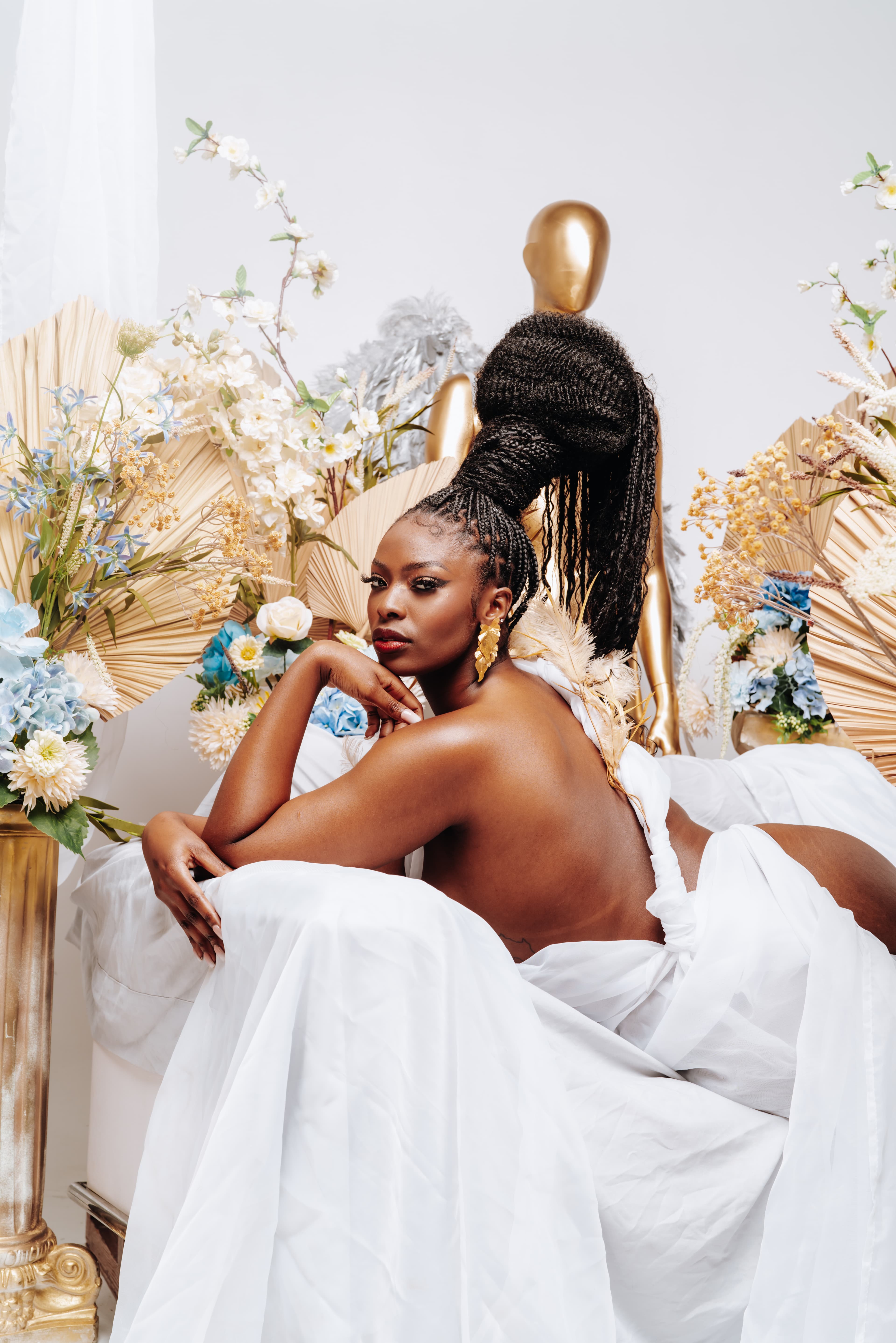 Portrait of a woman reclining among gold and floral arrangements.